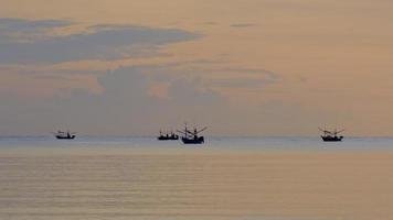 barcos de pesca flutuando no mar durante o pôr do sol na tailândia. veleiro na baía ao pôr do sol. video