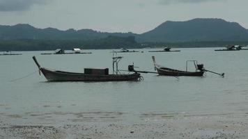 Fishing boats moored in a local fishing jetty on Yao Yai Island, Phang Nga, Thailand. fishing boats at the beach and waves. video