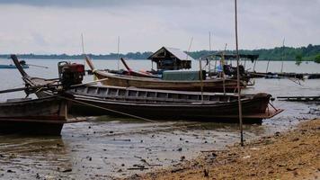 barcos de pesca amarrados en un embarcadero de pesca local en la isla de yao yai, phang nga, tailandia. barcos de pesca en la playa y las olas. video