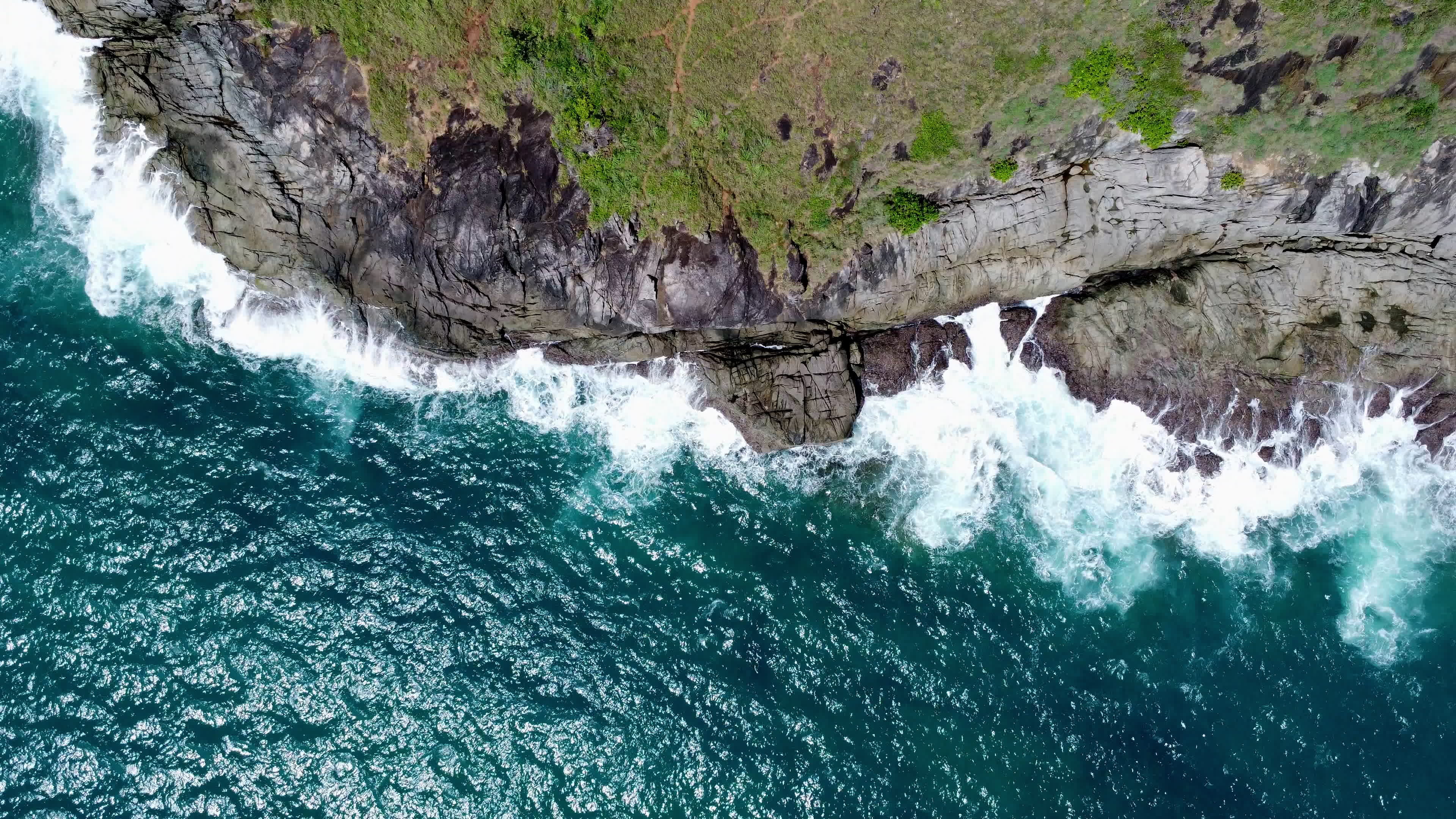 Aerial view of sea waves crashing on rocks cliff in the blue ocean Top Aerial view of sea waves crashing on rocks cliff in the blue ocean Top