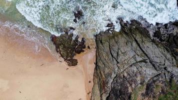 vista aérea de las olas del mar rompiendo en el acantilado de rocas en el océano azul. vista superior de las rocas costeras en el océano de phuket. punto de vista del paisaje del cabo laem phromthep por la mañana. video