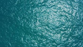 vue aérienne des vagues de la mer se brisant sur la falaise rocheuse dans l'océan bleu. vue de dessus des rochers côtiers dans l'océan de phuket. point de vue paysage du cap laem phromthep le matin. video