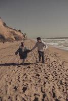 el hombre y la mujer se disfrutan, corren a lo largo de la orilla del mar foto