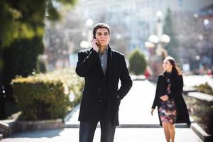 businessman talking on the phone while woman comes to him photo