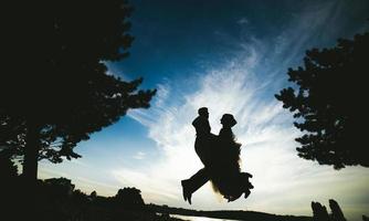 groom and bride jumping against the beautiful sky photo