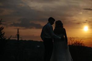 Silhouette of  wedding couple in field photo