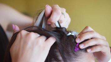 Process of braiding. Master weaves braids on head in a beauty salon, close up photo