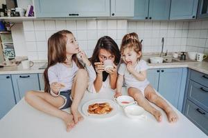 Mom and two daughters eat pancakes photo