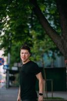 Young adult man in a black t-shirt and jeans walks on a city street photo