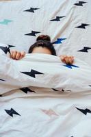 el primer plano de una encantadora joven yace en la cama cubierta con una manta. foto