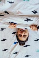 Closeup of Lovely young Woman Lies in Bed Covered with Blanket. photo