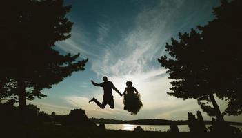 groom and bride jumping against the beautiful sky photo