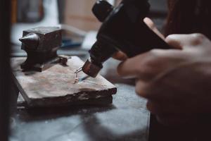 In the workshop, a woman jeweler is busy soldering jewelry photo