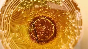 kohlensäurehaltige Flüssigkeit in einem Glas von goldener Farbe, durch das Sie den Boden sehen können. video