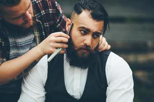 barber shaves a bearded man in vintage atmosphere photo