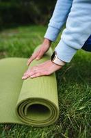 Close-up of woman folding roll fitness after working out in the park photo