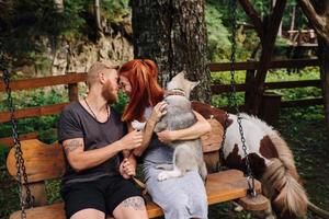 beautiful couple together with dog on a swing photo