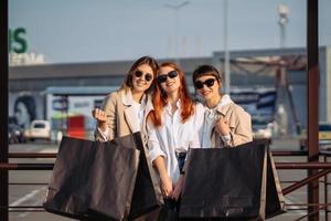 mujeres jóvenes con bolsas de compras en una parada de autobús foto