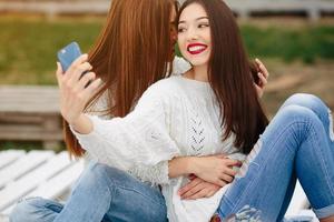 Two girls making selfie on the bench photo