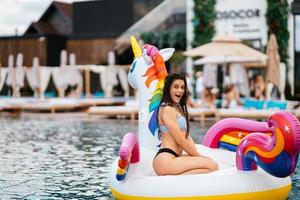 Woman on inflatable unicorn toy mattress float in pool. photo