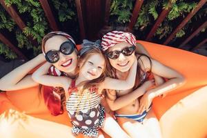 hermosa madre con dos hijas sentada en un salón naranja foto