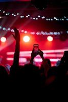 persona cerca de grabar video con teléfono inteligente durante un concierto. foto