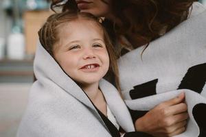 Cute little girl and her beautiful young mom hug each other photo