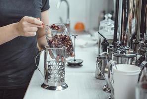 Pour dry tea leaves into the glass container of the tea press maker photo