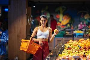 young woman do shopping in supermarket. choosing apples in store photo