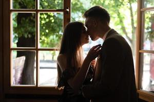 joven pareja enamorada de pie junto a la ventana foto