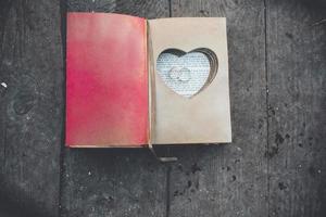 encantador libro vintage con corazón hecho a mano en el que descansa el anillo. foto