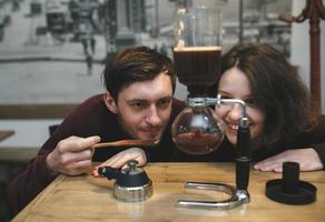 Vintage couple preparing coffee with vacuum coffee maker.Coffee shop photo