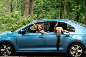 Two girlfriends fool around and laughing together in a car photo