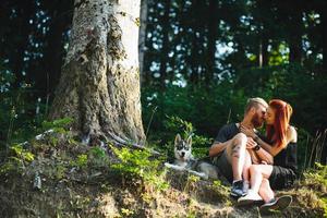 beautiful couple sitting in a forest near the tree photo