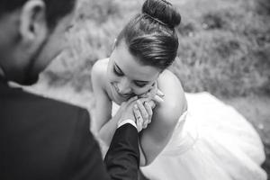 groom gently touches the face of his bride photo