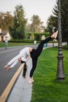 Attractive skinny woman doing a backbend while showing a somersault. photo