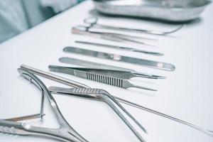 Several surgical instruments lie on a white table photo