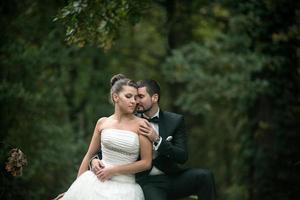 hermosa pareja de bodas sentada en el bosque foto