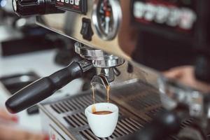 Professional espresso machine pouring fresh coffee into white ceramic cup photo