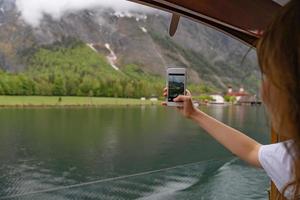 turista intenta tomar fotos con su teléfono inteligente en el lago hallstatter