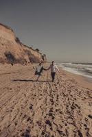 el hombre y la mujer se disfrutan, corren a lo largo de la orilla del mar foto