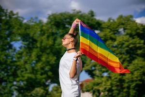 mujer joven ondeando la bandera del orgullo lgbt en el parque. foto