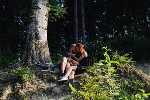 beautiful couple sitting in a forest near the tree photo