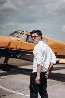 A man standing on the background of a small single engine plane. photo