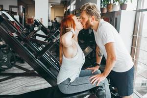 chico besa a la novia en el entrenamiento en el gimnasio foto