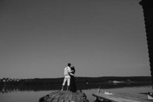 abrazando al hombre y a la mujer enamorados en el muelle de madera foto