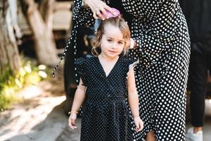 A young mother combs her little daughter's hair photo