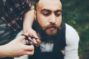 barbero afeita a un hombre barbudo foto