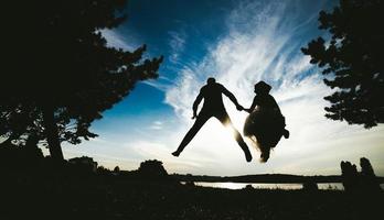 groom and bride jumping against the beautiful sky photo