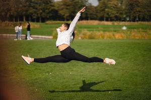 Sport girl jumping in the air on nature demonstrate perfect stretching. photo